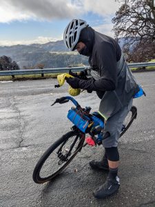 A cyclist practicing smart bike tour packing changes out a wet layer for a dry one
