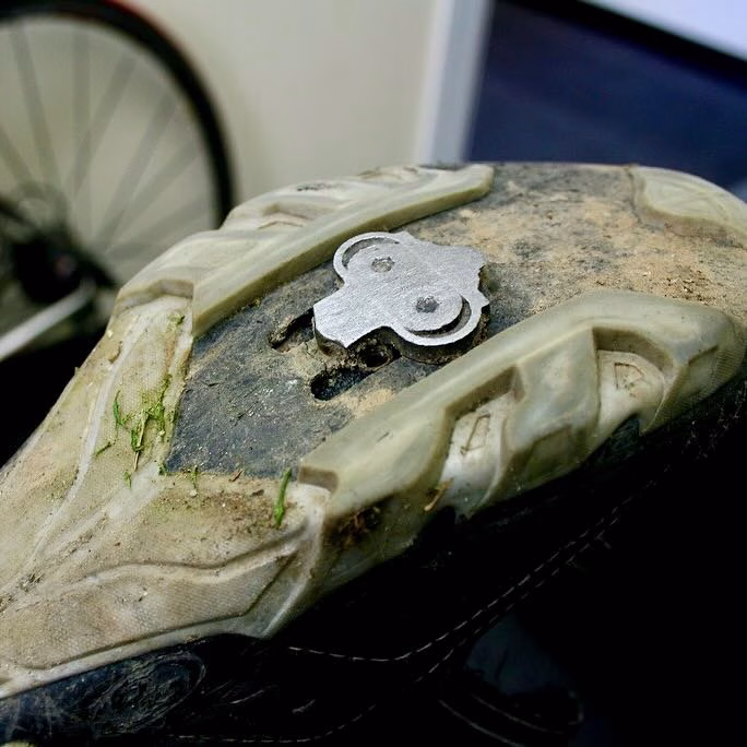 A worn Shimano SPD cleat on a cycling shoe